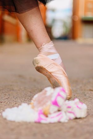 Ballet shoes and pink confetti scattered on concrete ground.