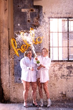 Group celebrating with champagne spraying in an industrial loft space.