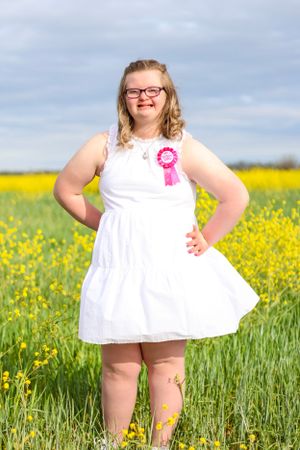 Person in white dress standing in field of blooming yellow wildflowers.