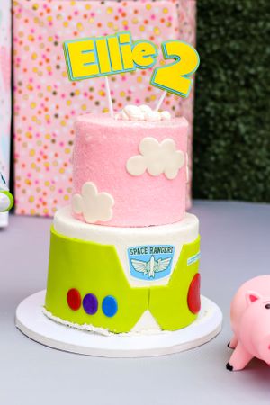 Toy Story themed birthday cake with pink and green frosting on white table.