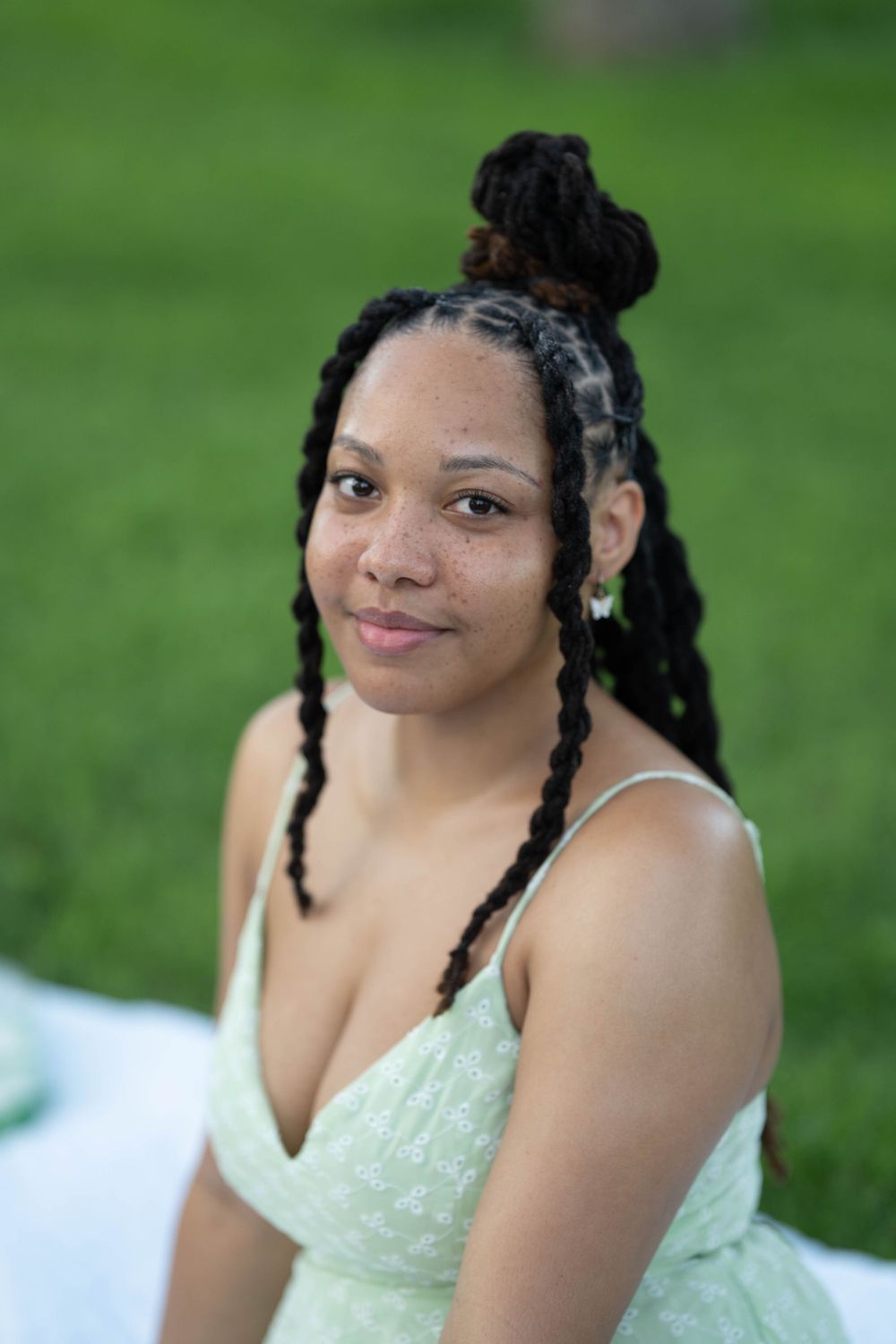 A person in a mint sundress poses for a portrait outdoors.