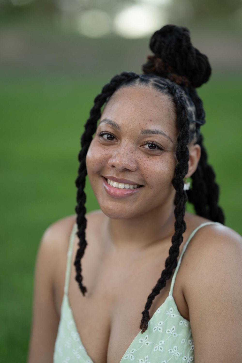 A close-up outdoor portrait showing someone wearing a mint dress with braided hairstyle.