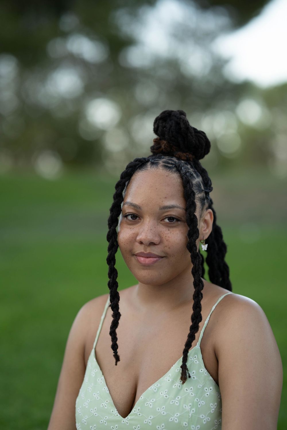A portrait of someone wearing a mint green dress outdoors with braided hair styled in a bun.