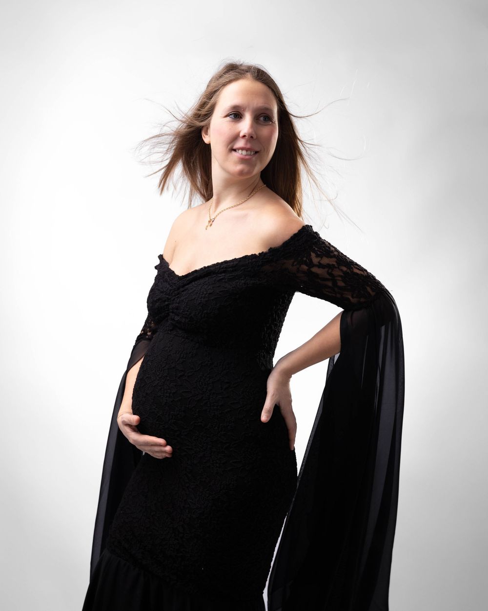 A person in a flowing black dress poses against a white background in a dynamic fashion photoshoot series.