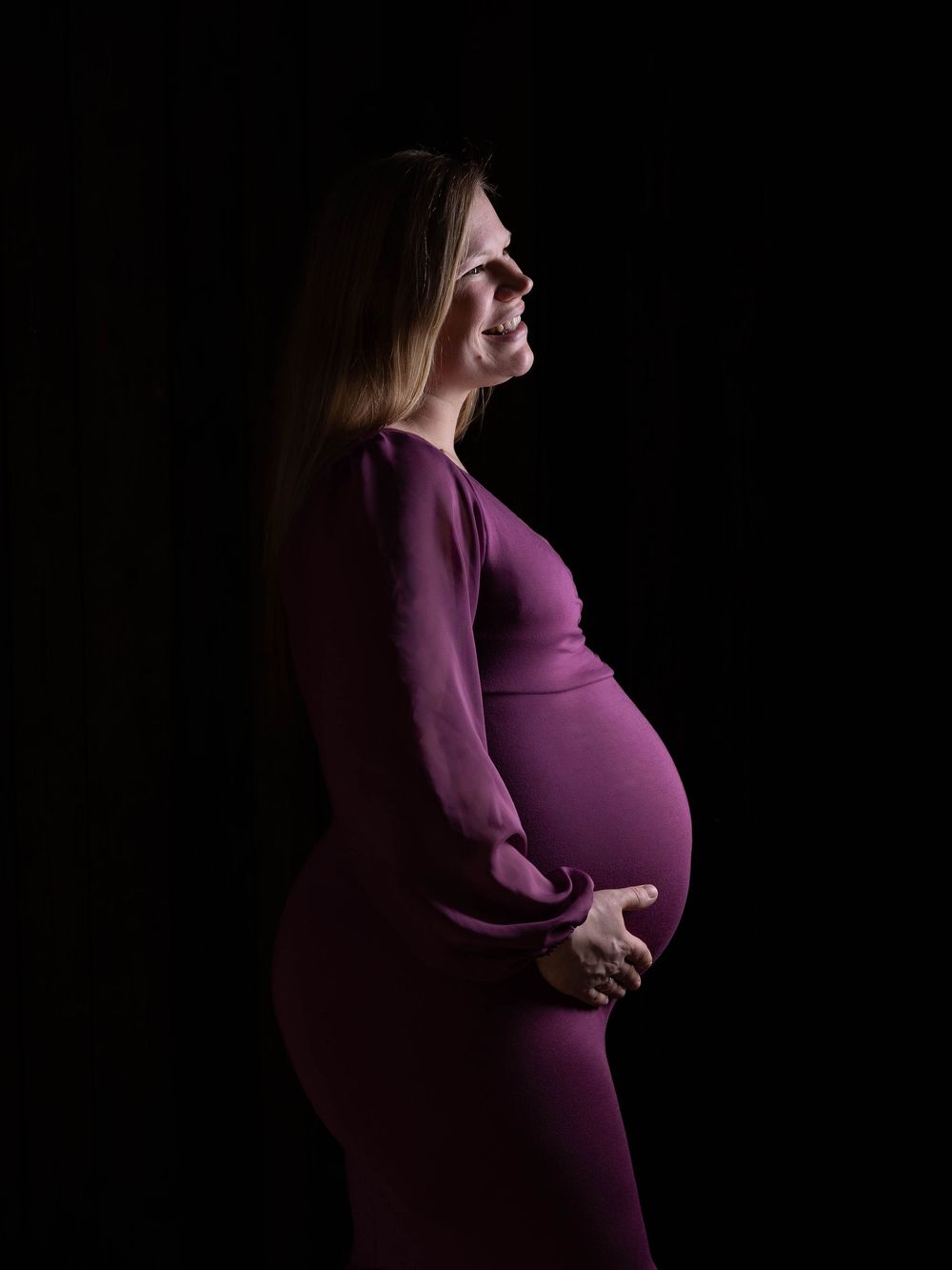A series of artistic maternity photos showing a pregnant woman in a purple dress against a dark background.