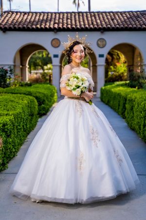 An elegant portrait in a white embellished ballgown with crown in a formal garden setting. sylmar.