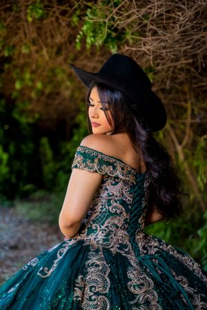 Detailed back view of a teal embellished gown paired with a black cowboy hat.
