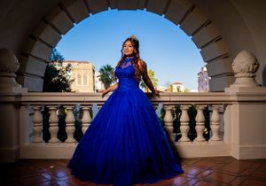 A stunning royal blue ball gown photographed against classic architecture and blue sky.