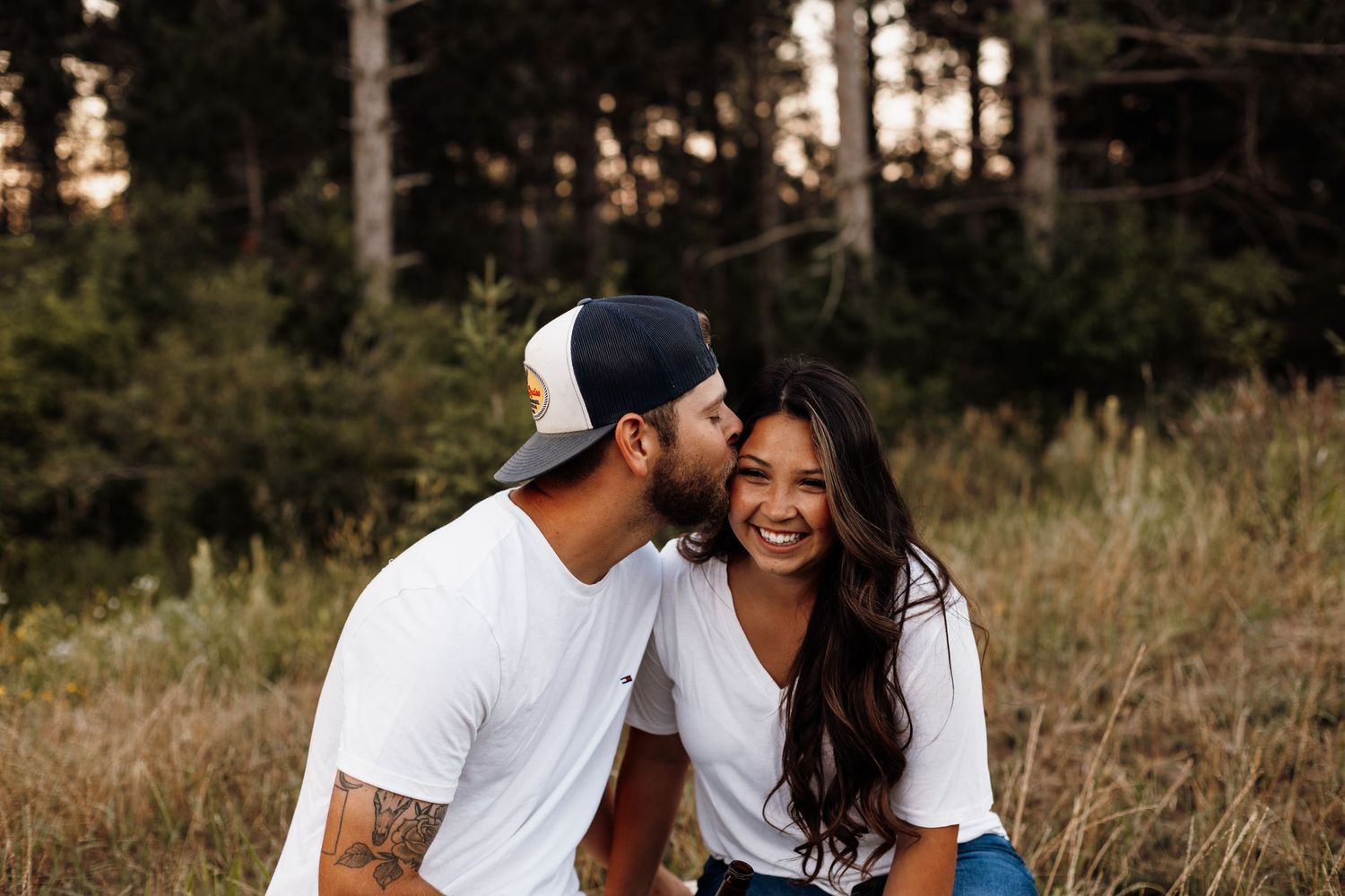 A couple shares a joyful moment together in a grassy field at sunset.