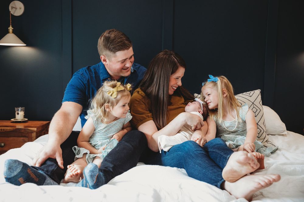 Family lounging together on bed during intimate lifestyle photoshoot.