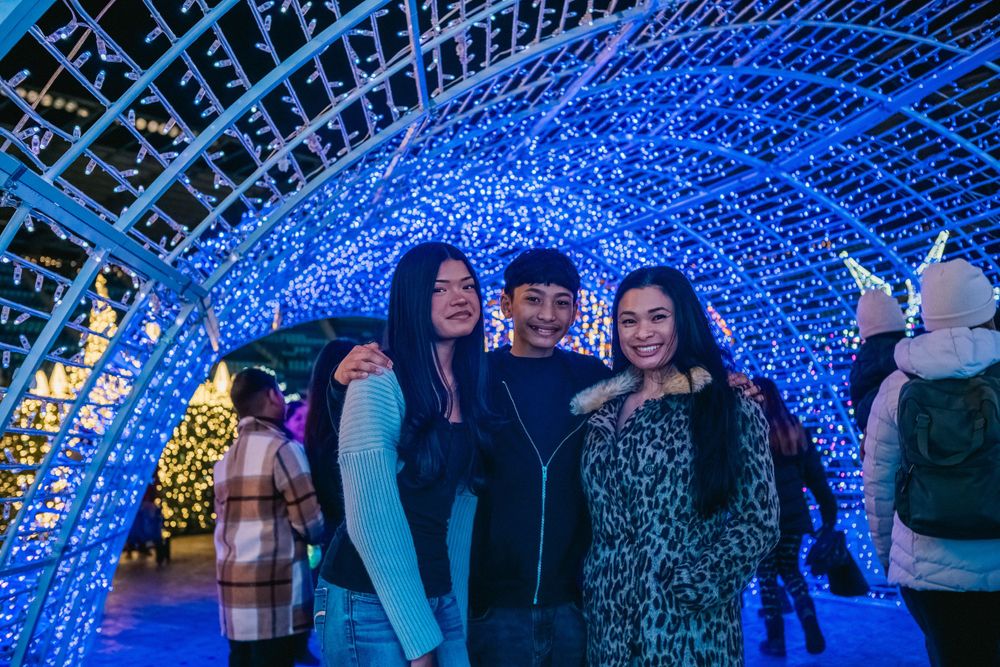 Visitors enjoy a holiday light tunnel with blue LED lights creating an immersive archway.