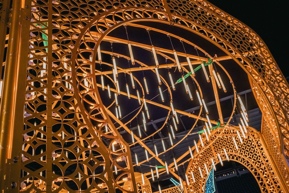 An intricate golden architectural structure illuminated with holiday lights at night.