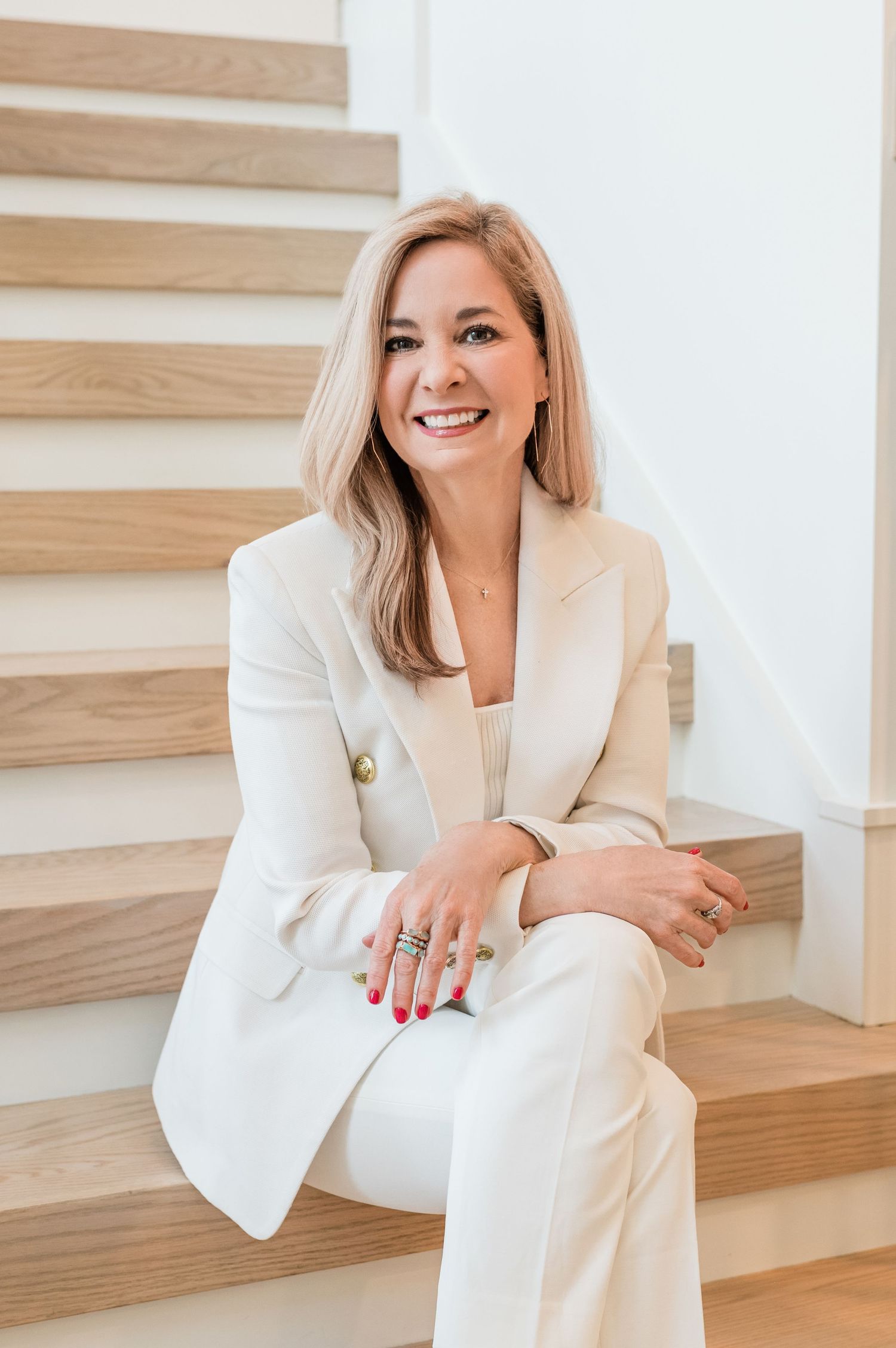 Professional headshots on wooden stairs wearing crisp white blazer.