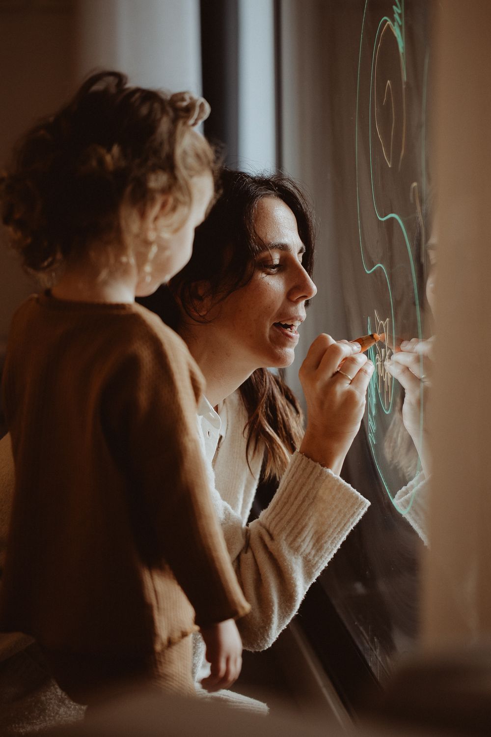 Drawing together on a window with artistic swirls visible in the soft lighting.
