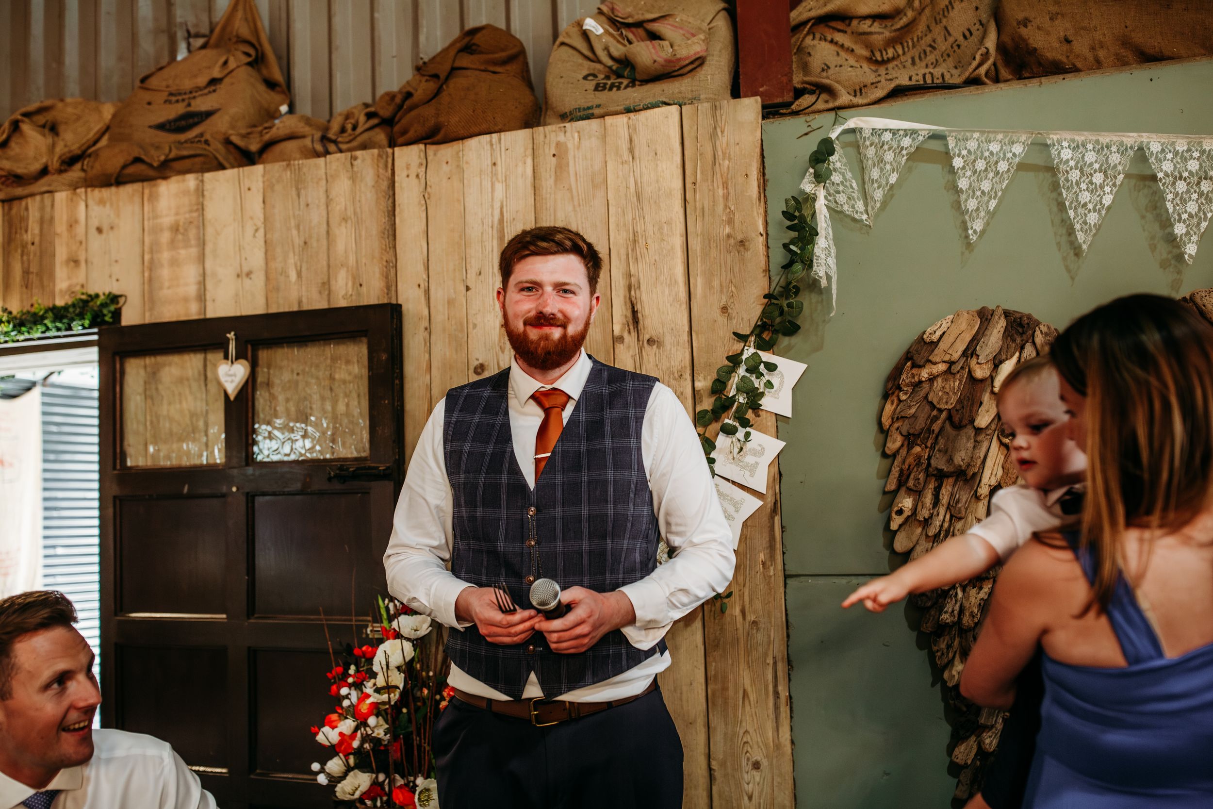 Reception speech in rustic barn venue with wooden walls and bunting decorations.