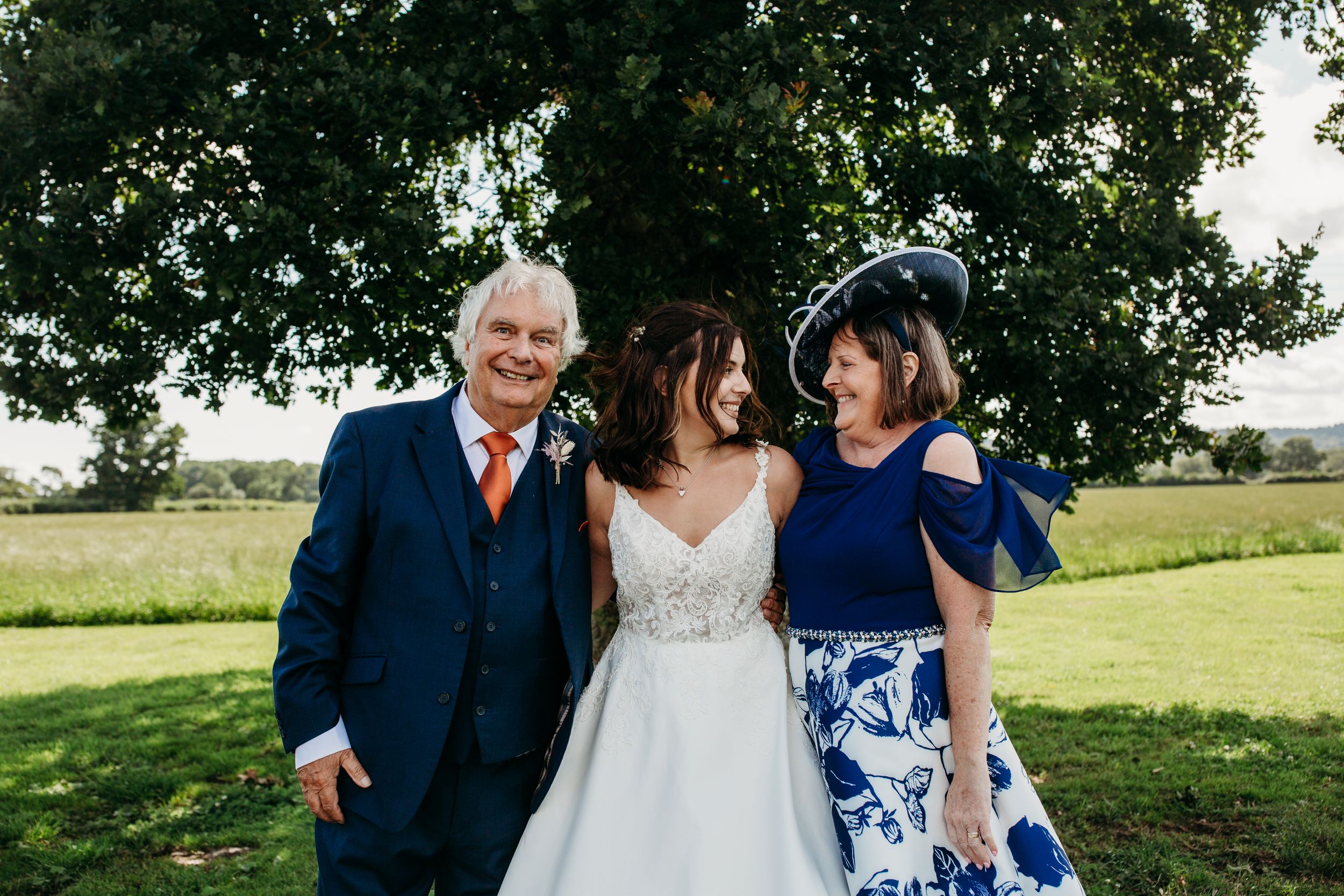 Outdoor wedding photo with couple and guests in navy blue attire.