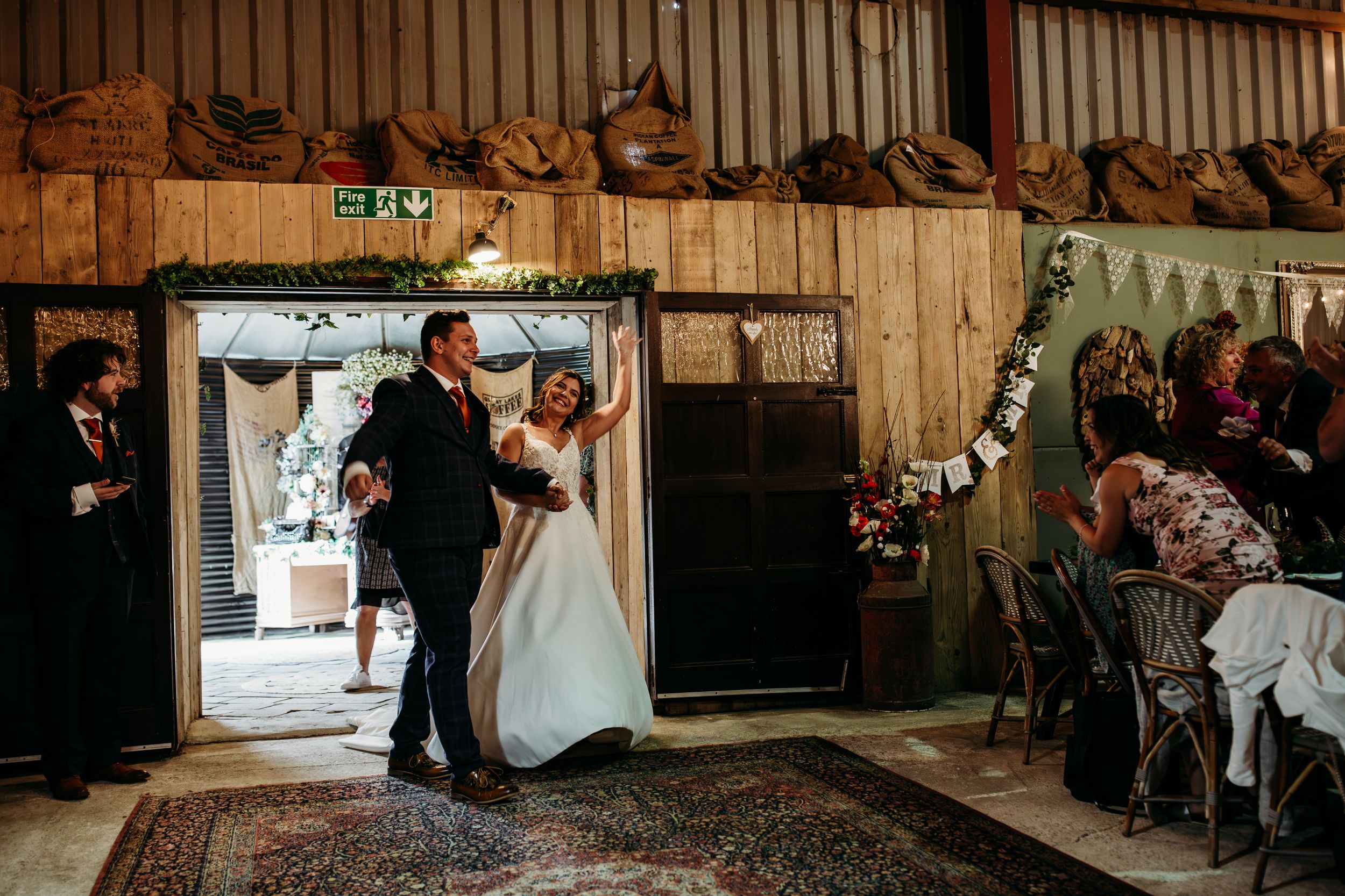 Grand entrance of couple into rustic barn wedding reception with string lights.