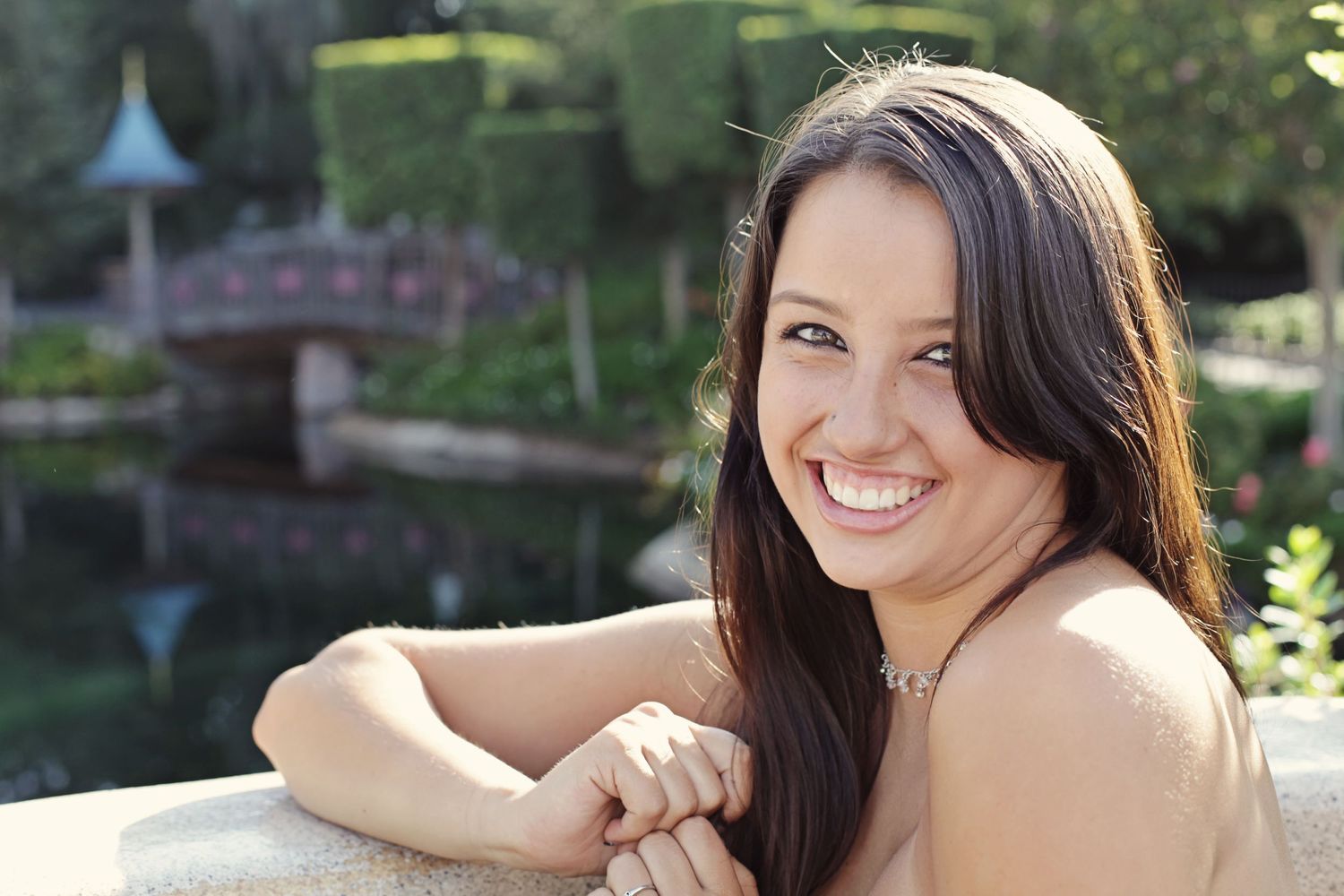 Portrait of woman smiling near decorative garden pond.