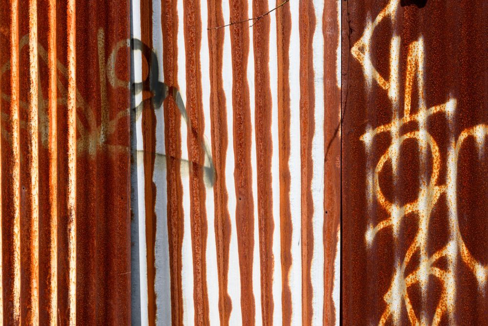 abstract rhythmic image of a rusted corrugated sheet with graffiti