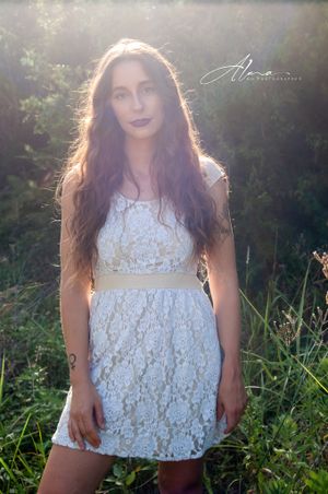 Ethereal outdoor portrait in white lace dress with sunlit background.