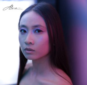 Artistic portrait with dramatic blue and pink lighting creating moody atmosphere.
