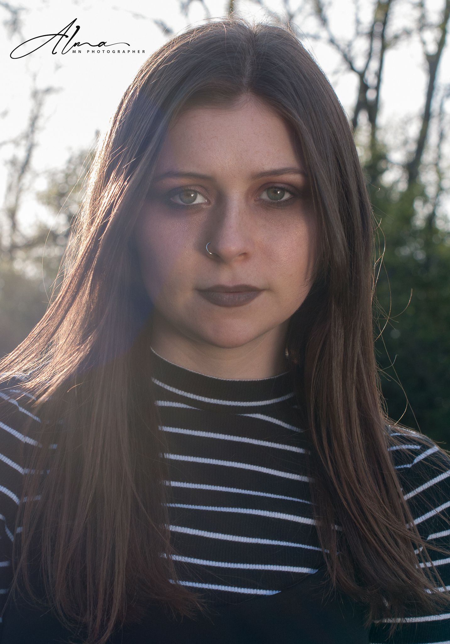 Close-up portrait in striped shirt with soft natural lighting and rustic background.