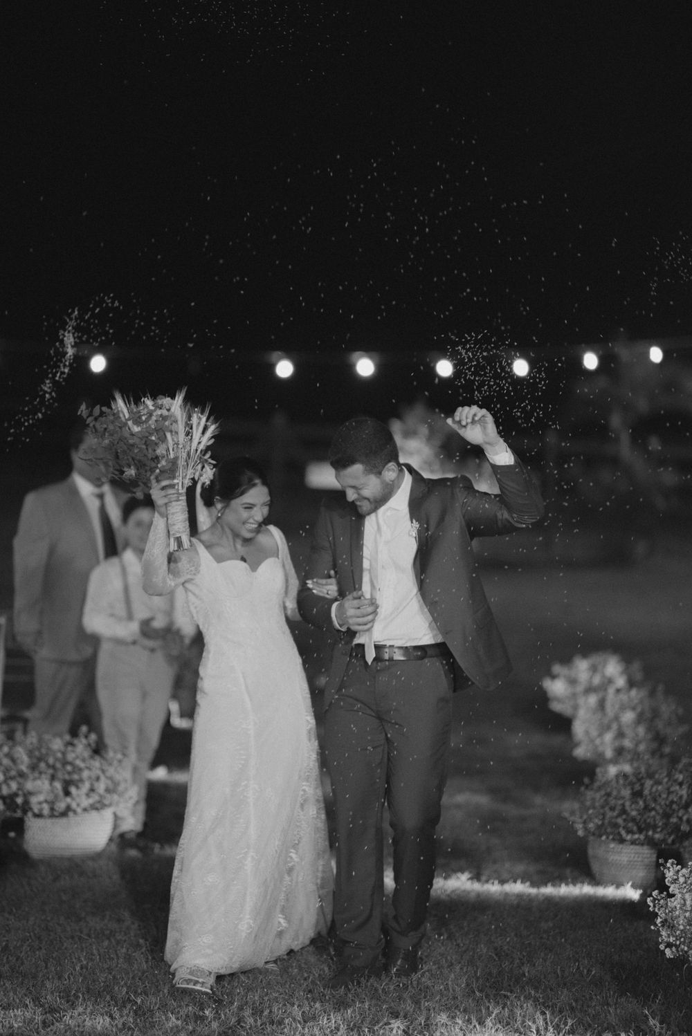 Newlyweds dancing under string lights at night during their wedding celebration.