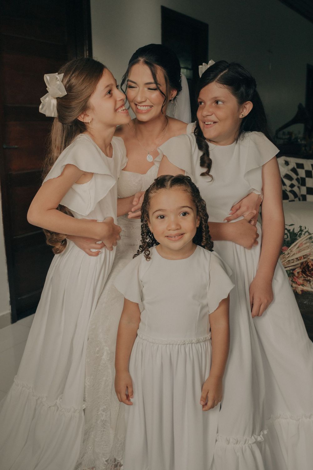 A group in white dresses share a joyful moment together during wedding preparations.