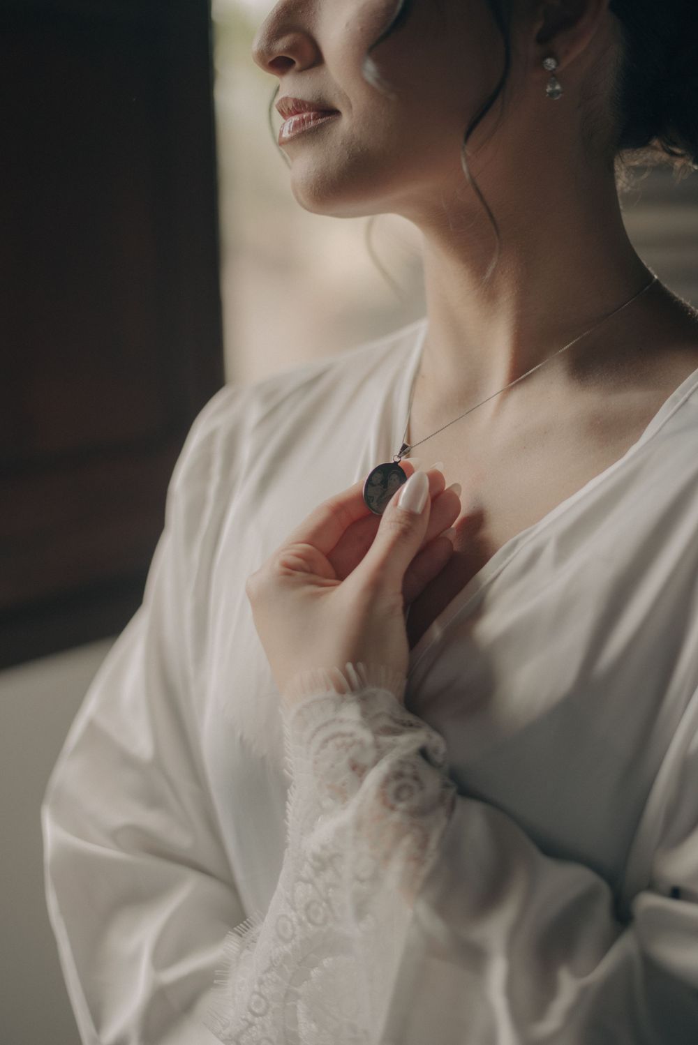 Close-up portrait of someone in white lace wearing delicate jewelry.