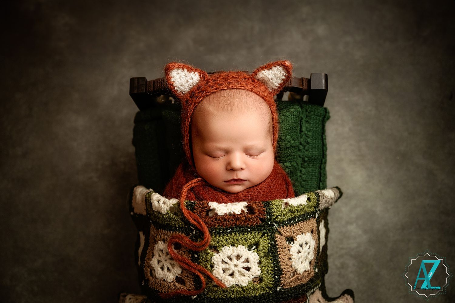 Sleeping baby wearing fox-themed bonnet in vintage green and white decorated basket.