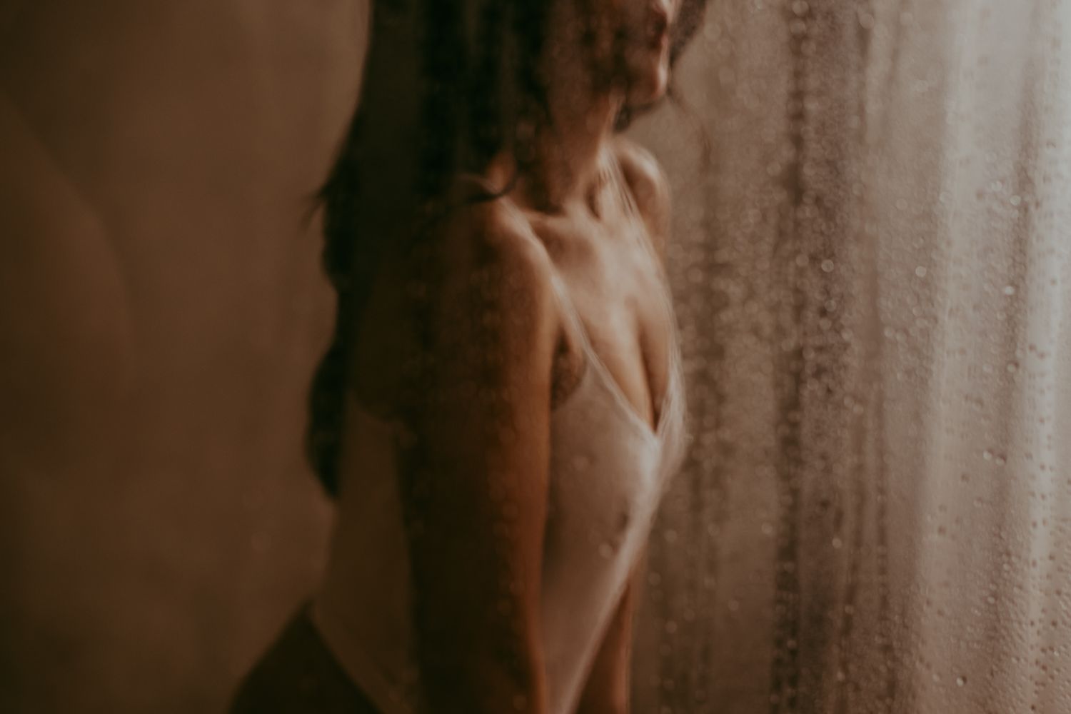 Atmospheric silhouette portrait through textured glass with warm tones.
