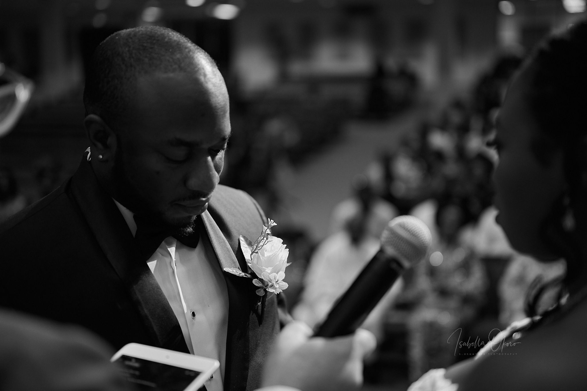 A close-up black and white photograph showing wedding guests reading from booklets during a ceremony.