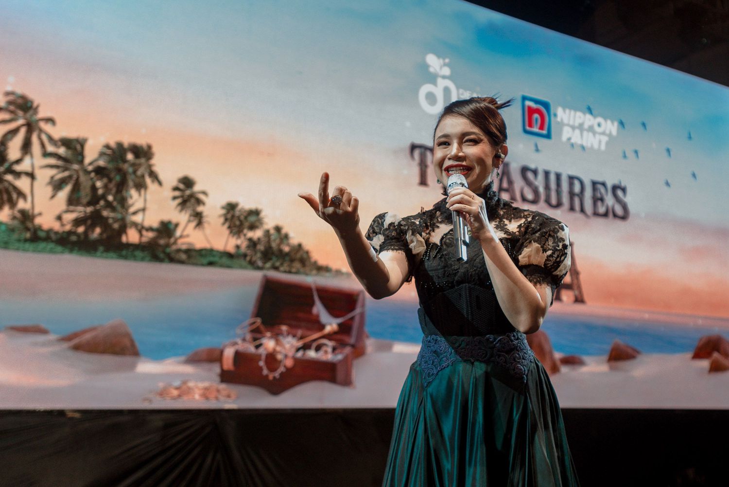 Stage performance against tropical beach backdrop with treasure chest projection.