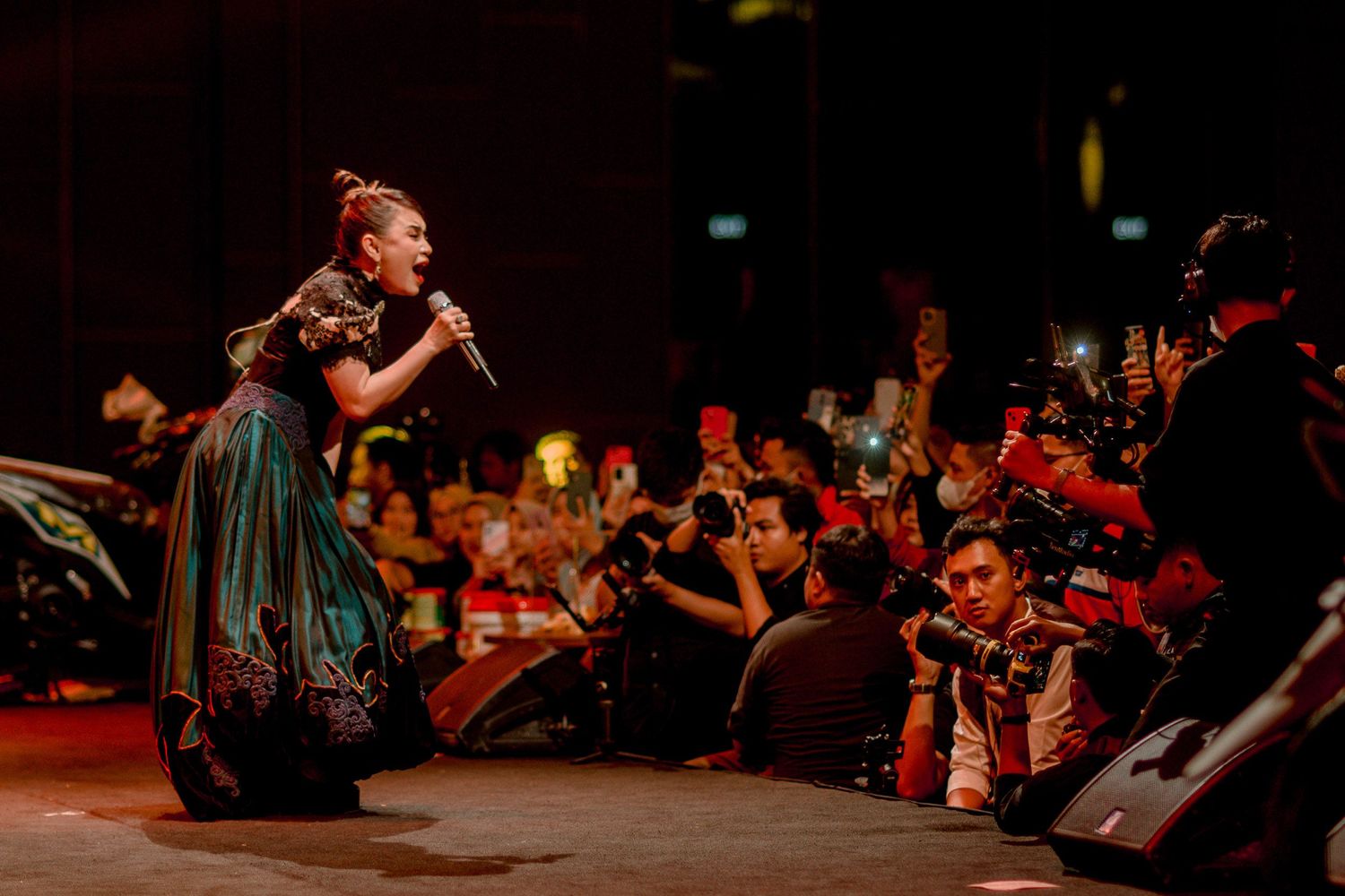 Concert performer in vintage dress engaging with excited crowd during live performance.