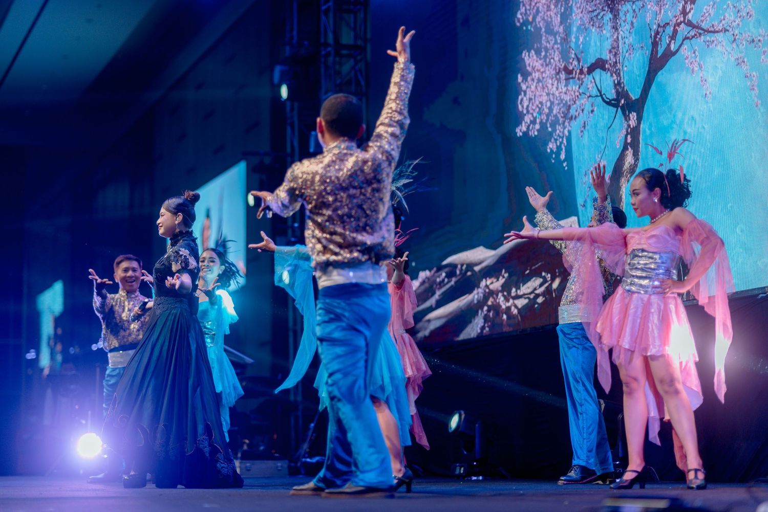 Dancers perform under blue stage lighting during a theatrical performance.