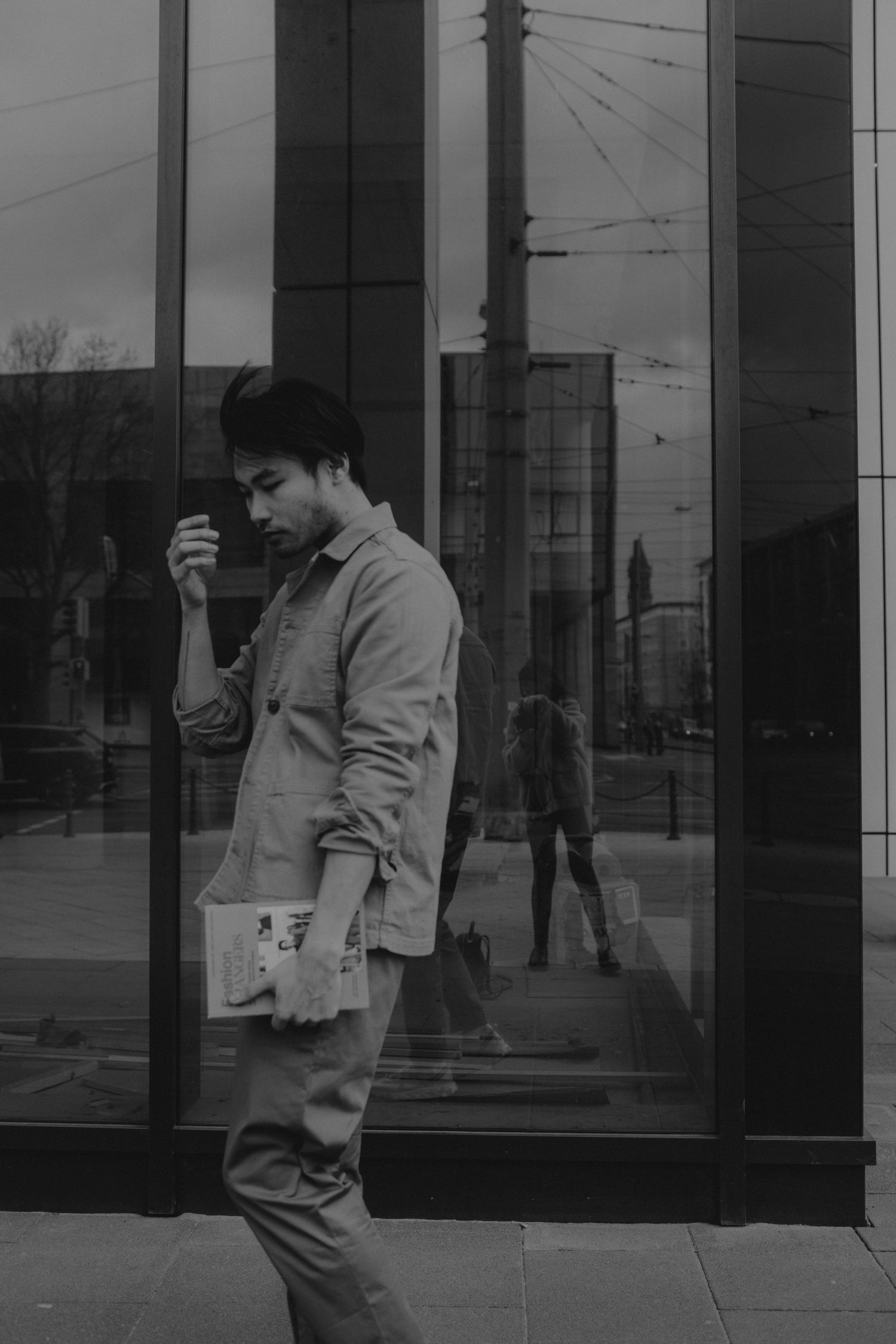 A moody black and white street scene with reflective glass windows and urban architecture.