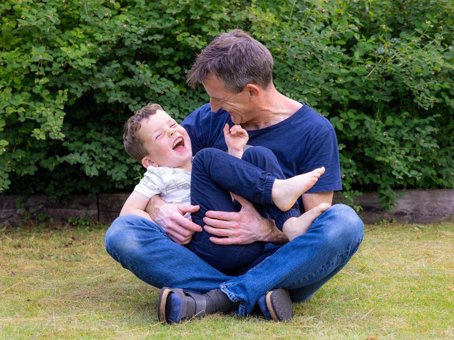 Joyful playtime between parent and child sitting on grass outdoors.