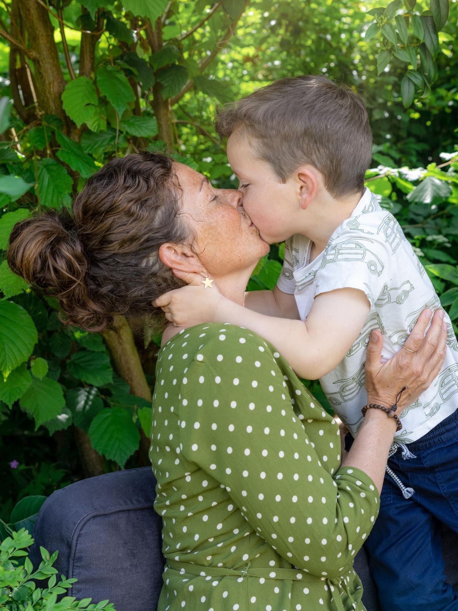 A tender moment shared between parent and child among green foliage in a garden setting.