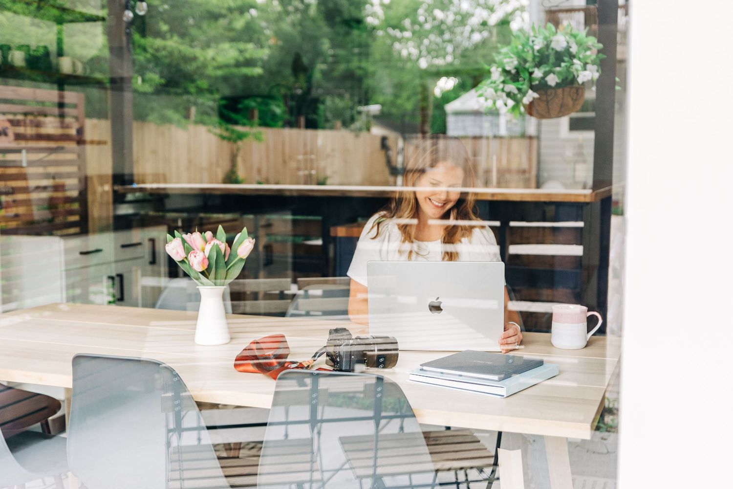 looking into glass at a woman looking at her laptop