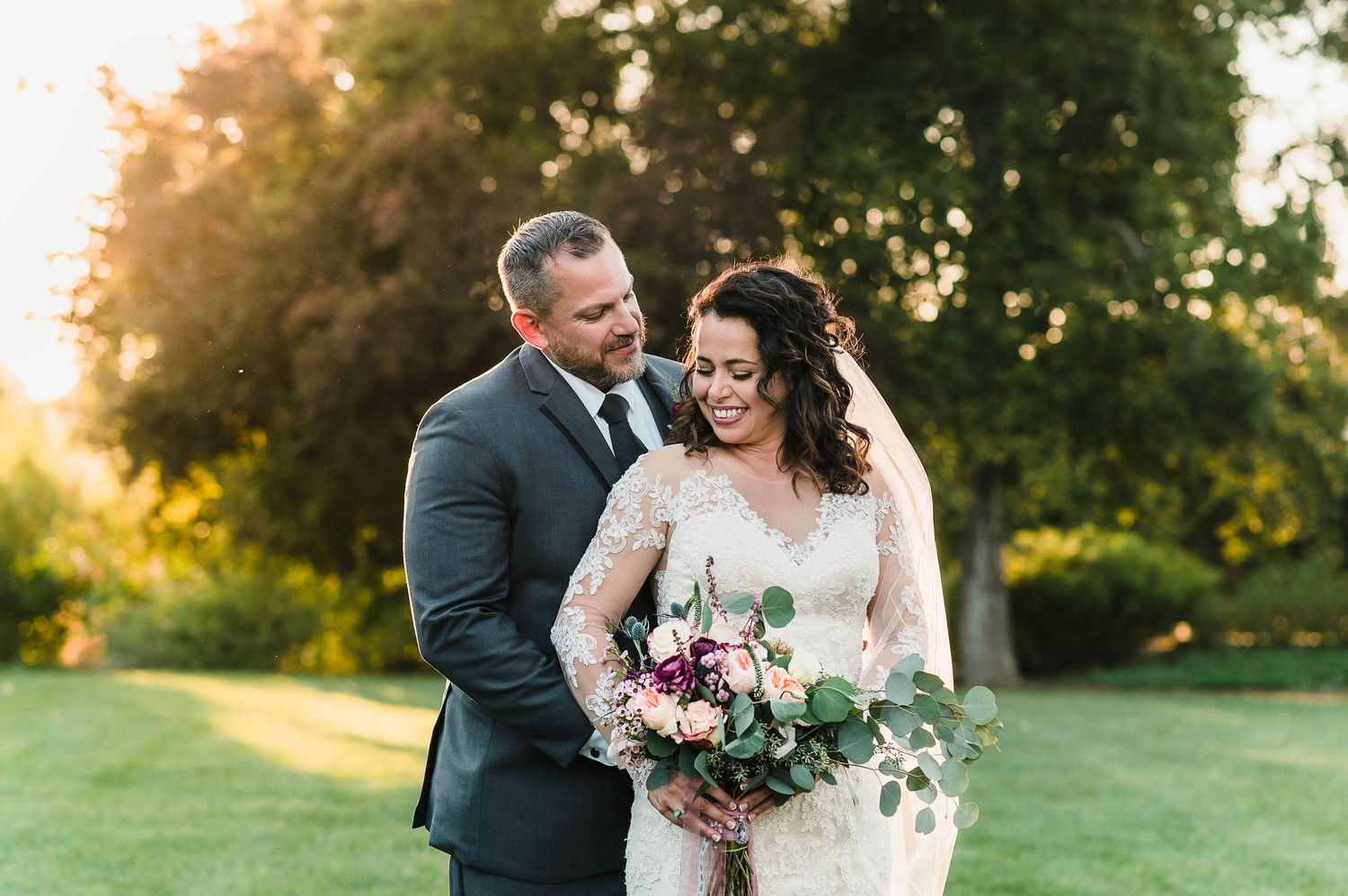 Sunset wedding portrait with beautiful floral bouquet in a lush garden setting.