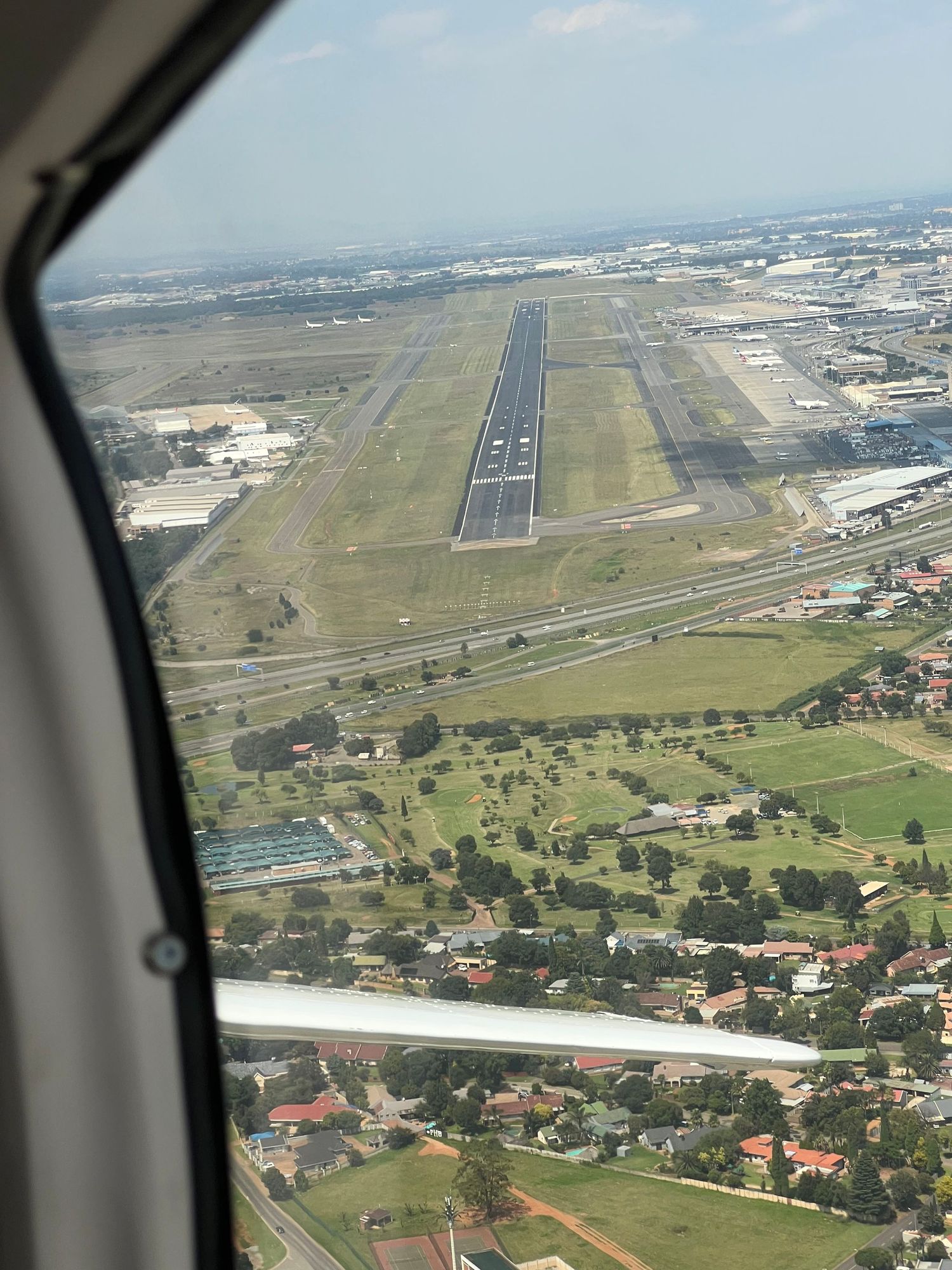 Aerial view of airport runway and surrounding residential area through airplane window.