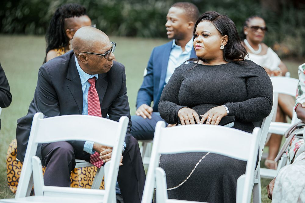 Wedding guests engaged in conversation while seated in white folding chairs.