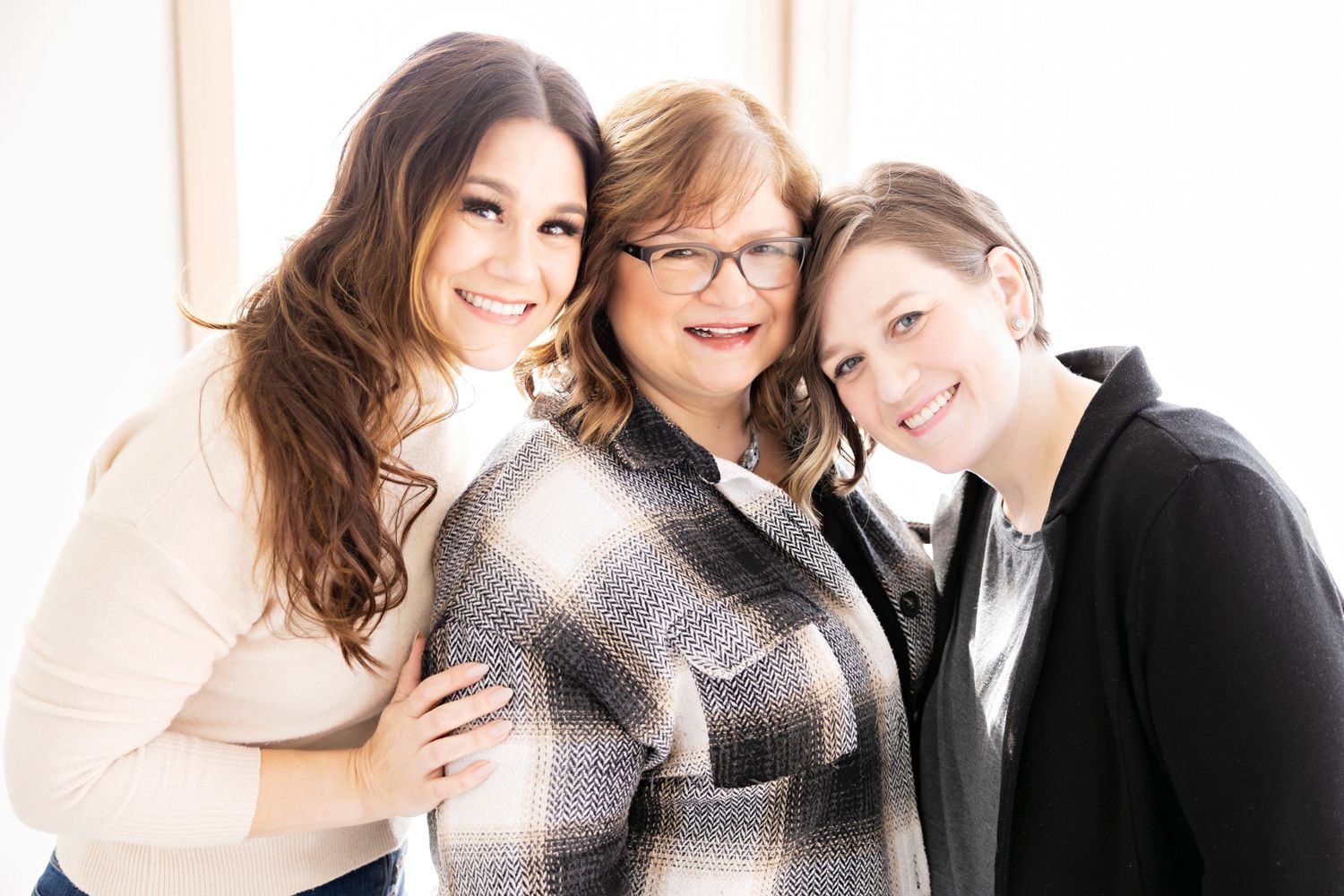 Three people posing together in warm casual setting.