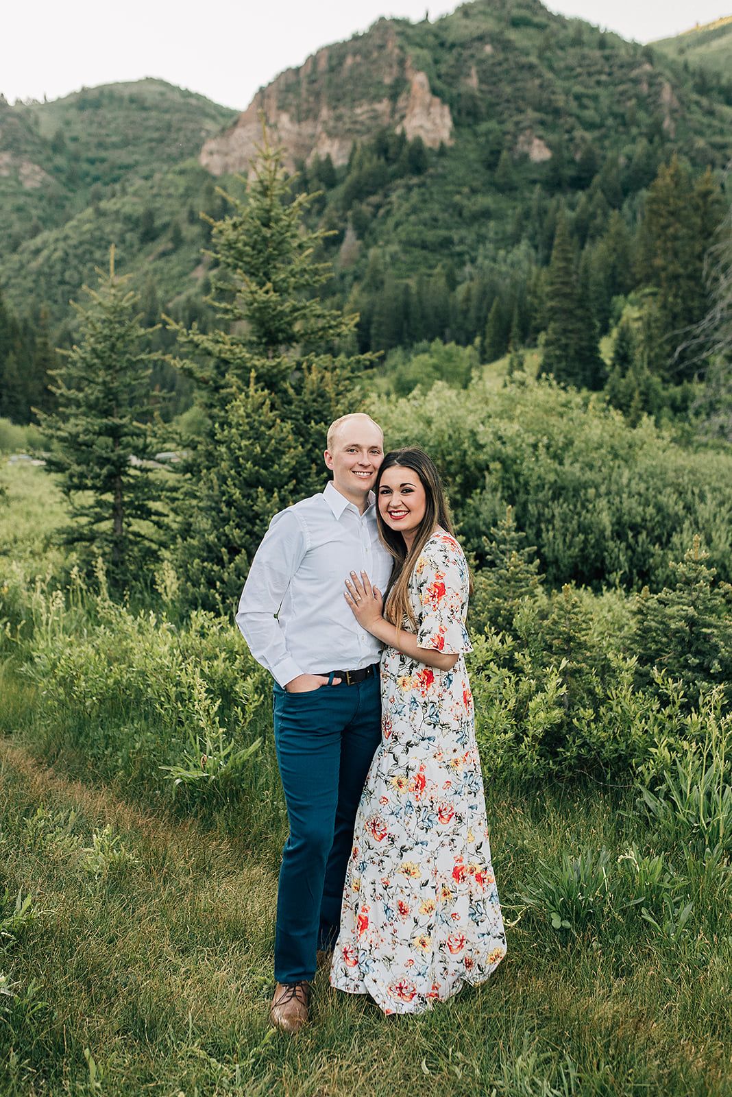 Spring portrait in a lush mountain setting with evergreen trees and rocky cliffs.