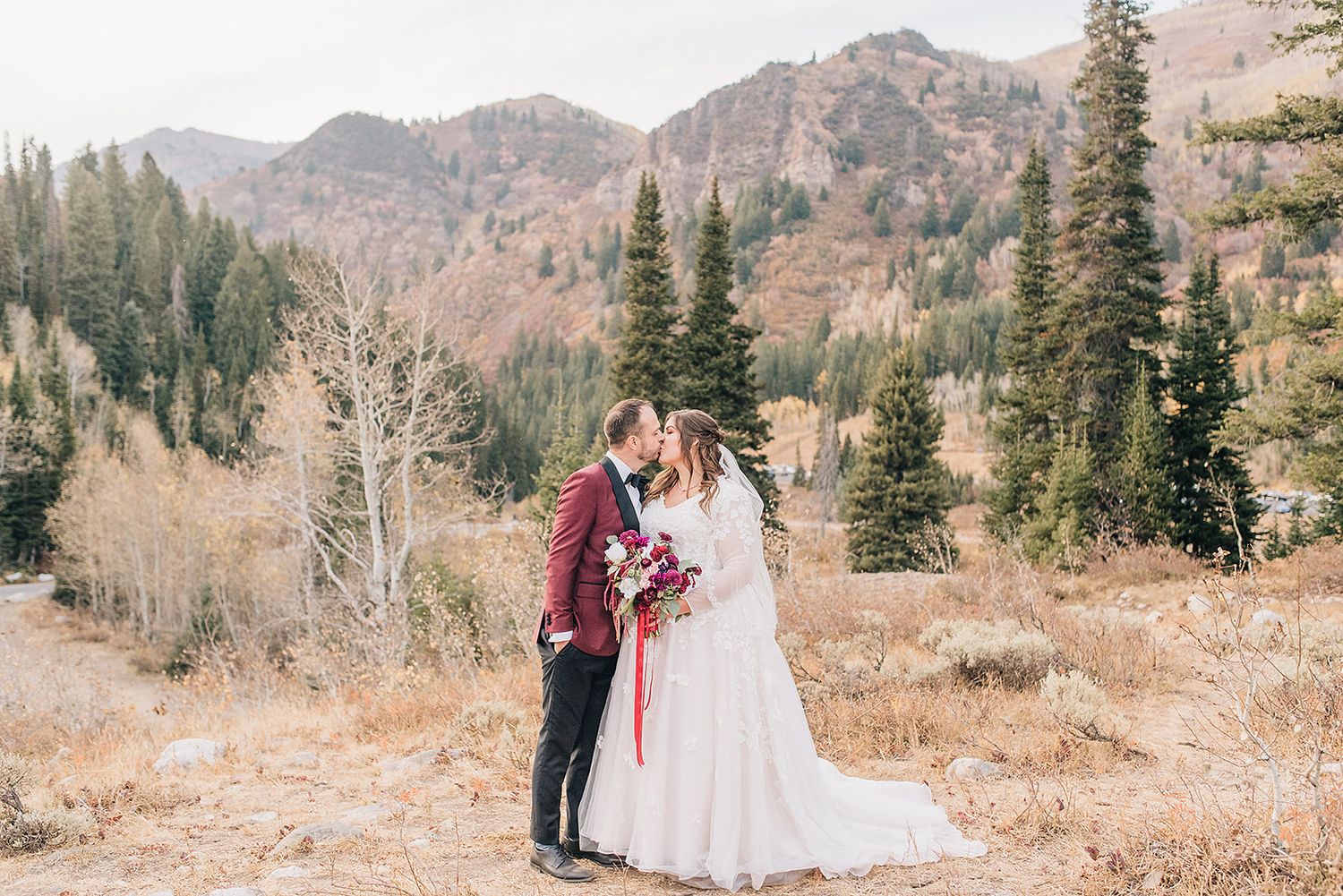 Intimate autumn mountain wedding photo with burgundy and white floral details.