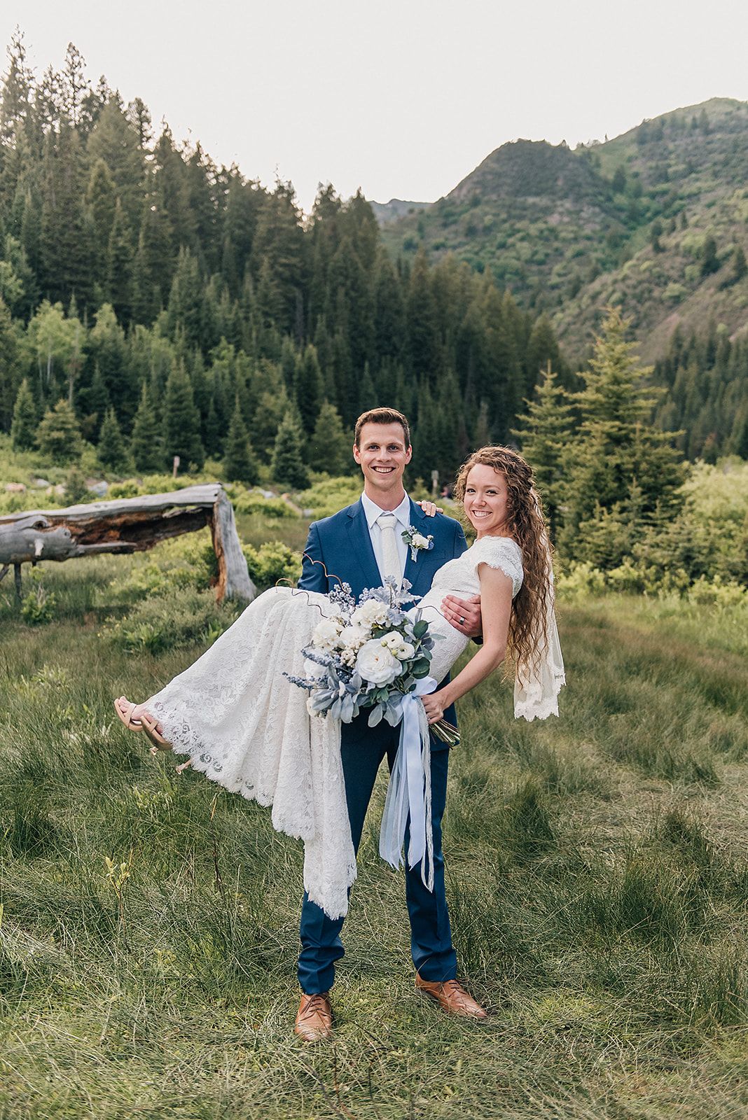 Wedding portrait in an alpine meadow with mountain views and carrying pose.