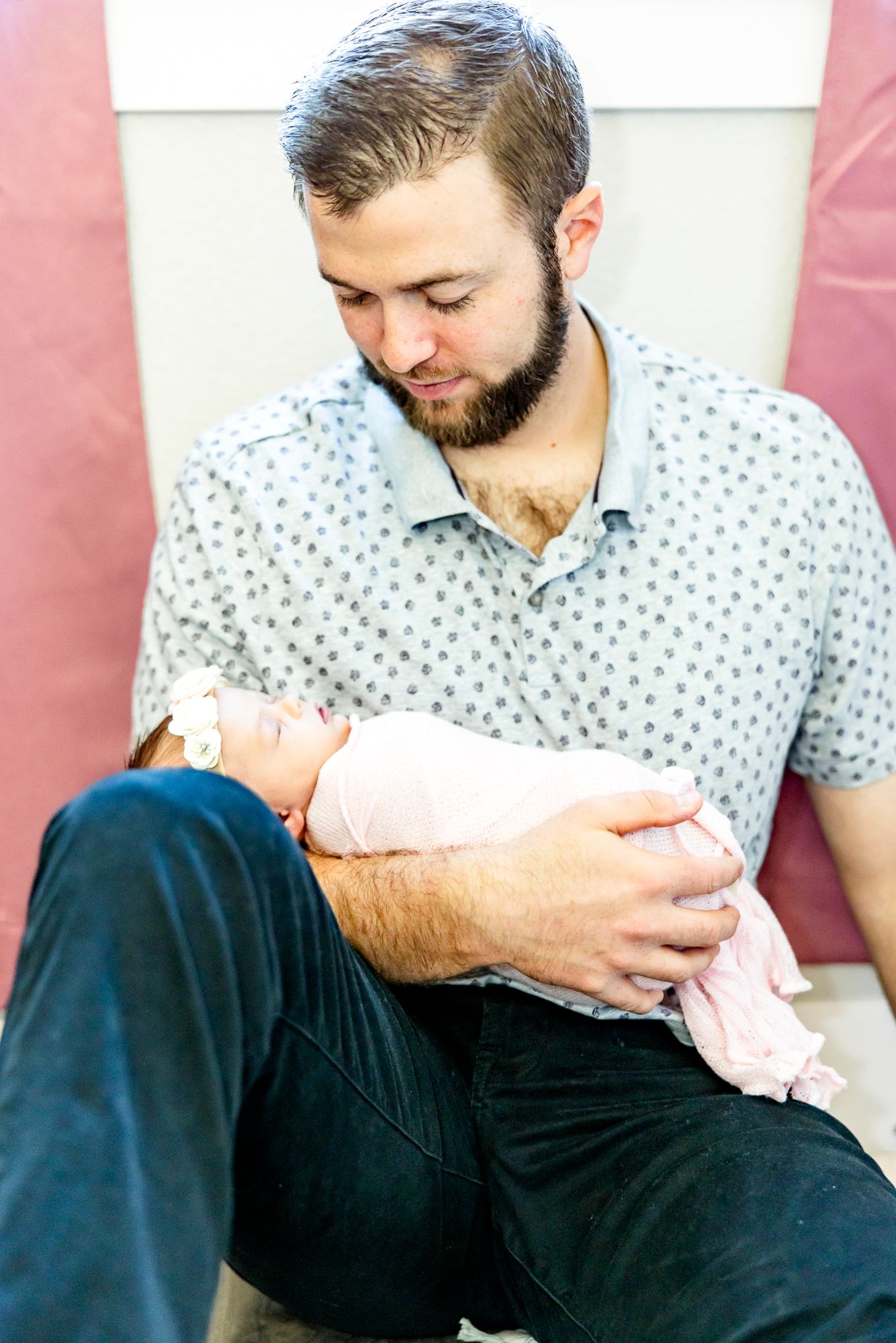 Dad holds his new baby girl and smiles down at her during newborn photos in Colorado Springs.