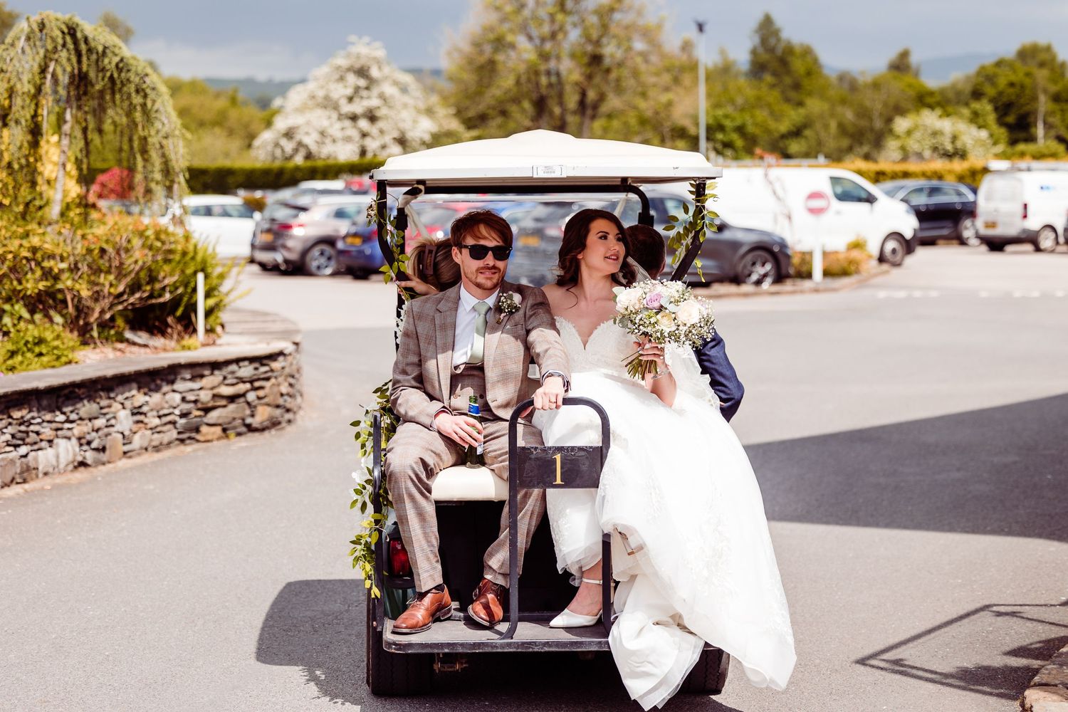 Bride and groom riding together in a golf cart at their wedding venue.