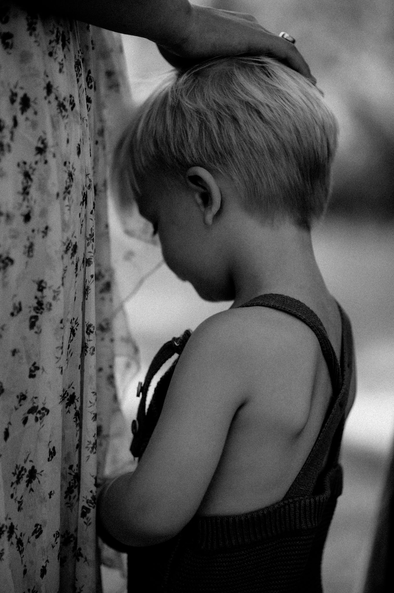 Black and white photo series showing a child's tender moment leaning against a textured wall.