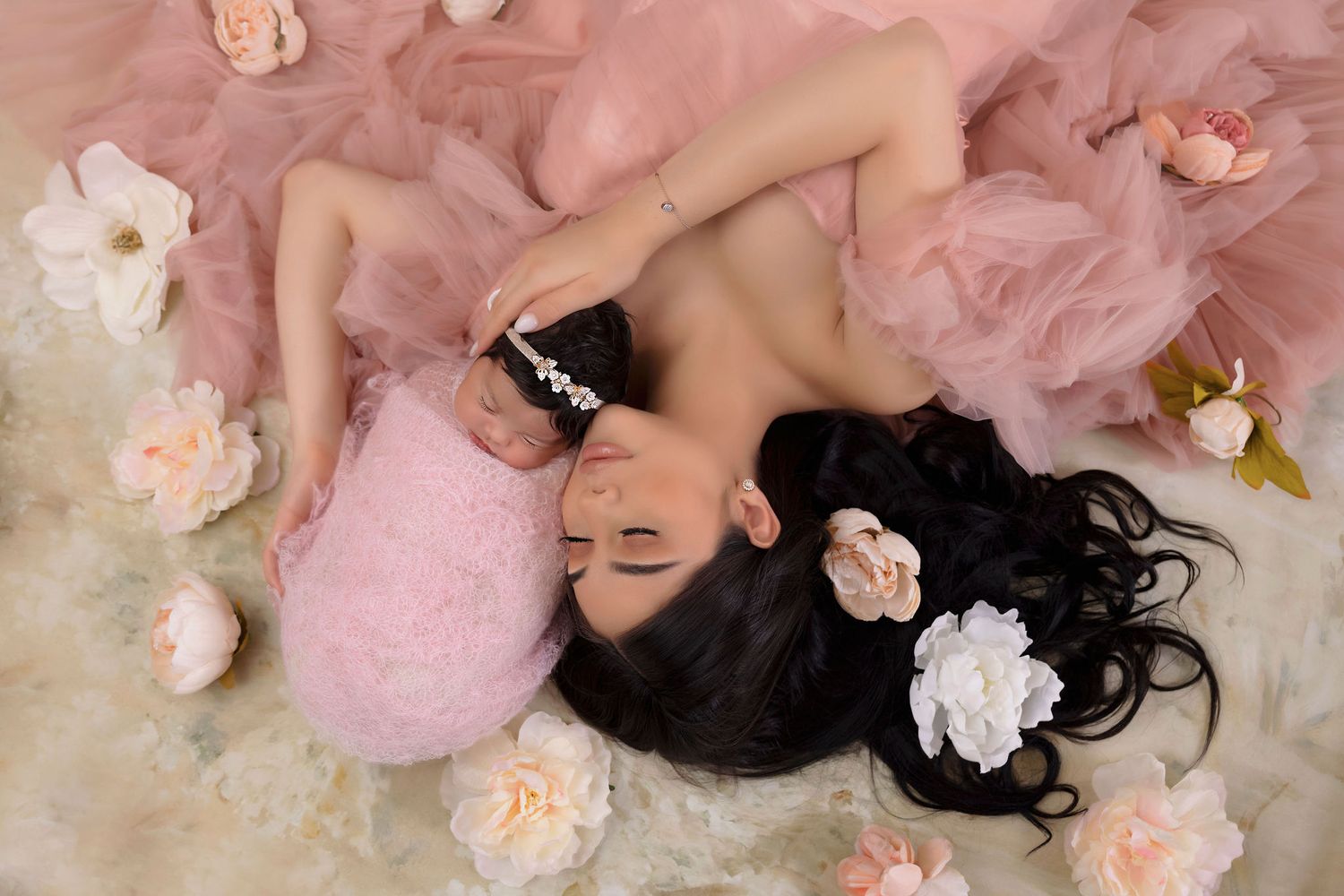An artistic portrait surrounded by soft pink tulle and delicate rose petals in a romantic setting.
